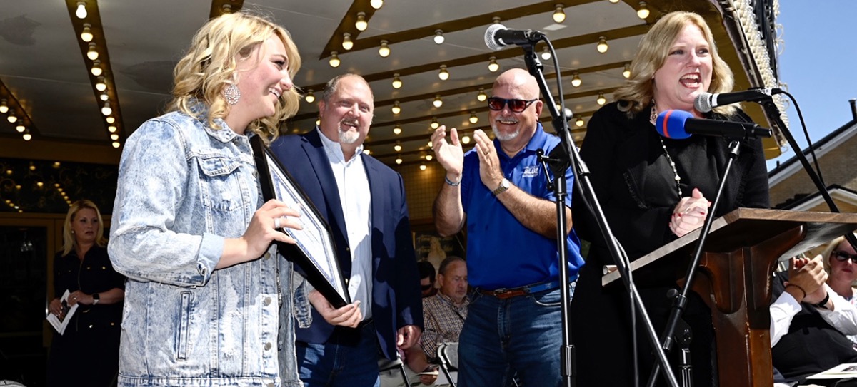 Odie on an outdoor stage at an award and certificate presentation